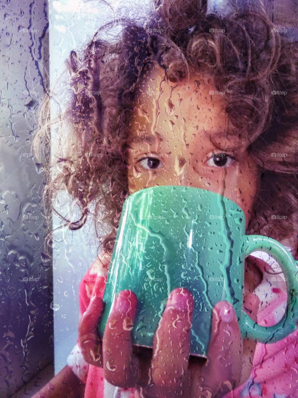 Girl having breakfast in green mug in rainy day.