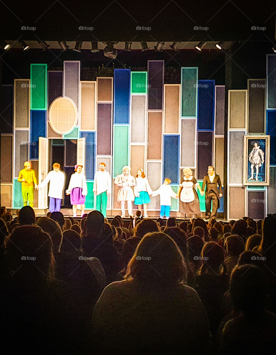 Moscow Theater, the end of the children's play. Silhouettes of applauding people against the backdrop of an illuminated scene with actors in costumes bowing to the viewer.
