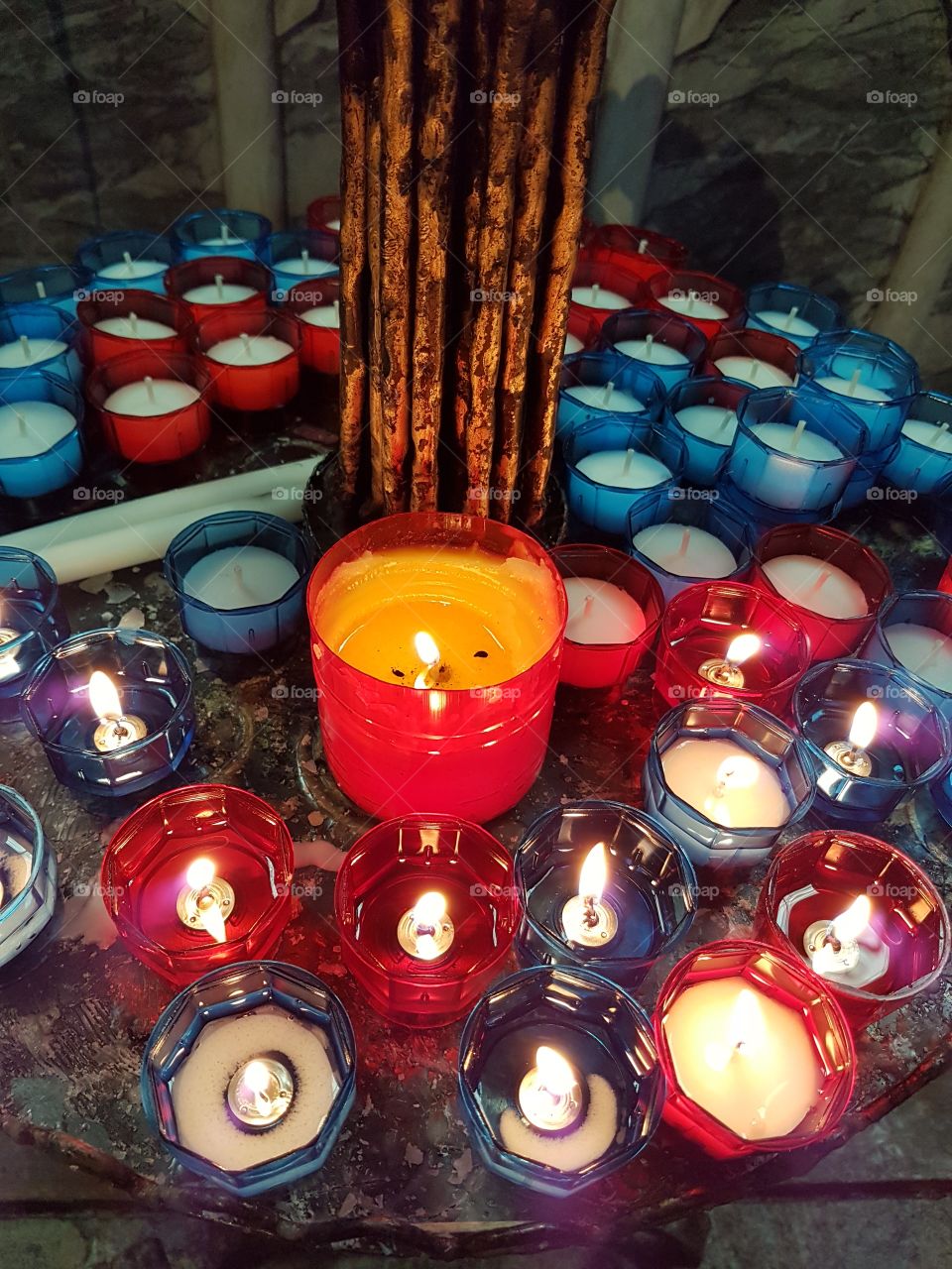 Lighted candles in a church interior, red and blue colors