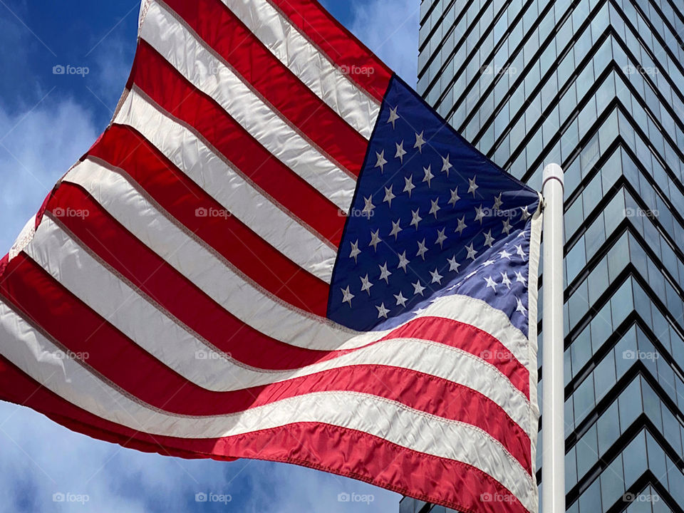 American flag flying beside a modern skyscraper 