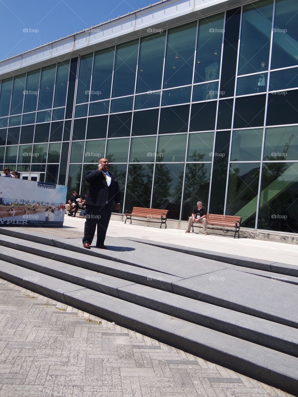 Business Man. Large man in business suit talks on a smart phone outside building. 