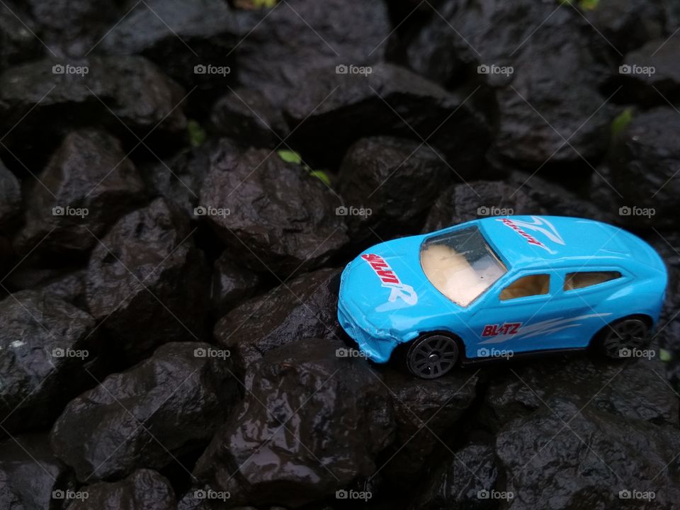 Blue car miniature toy on rocks