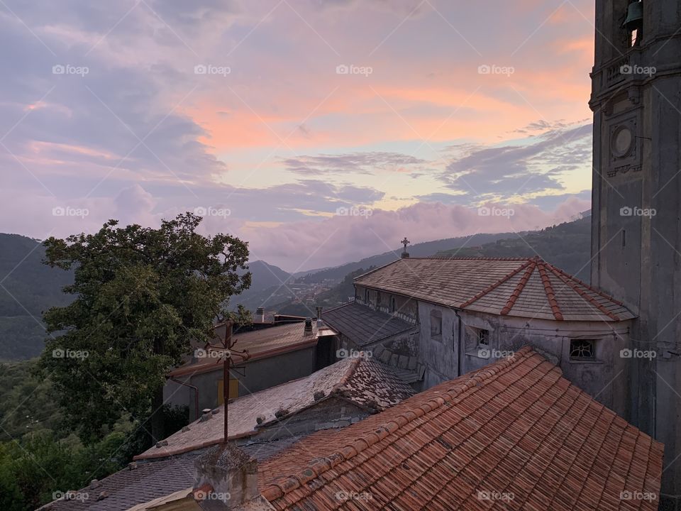 Beautiful view from a window in Liguria. Shades of purple and pink on a church and in the sky.