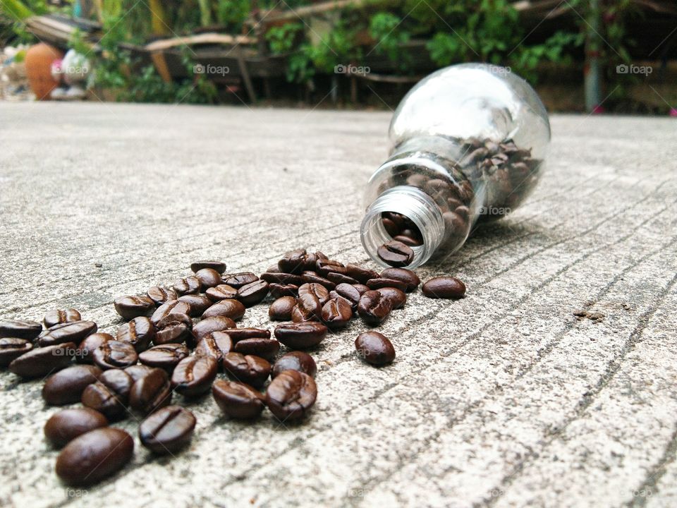 coffee beans in glass bottle on concrete floor