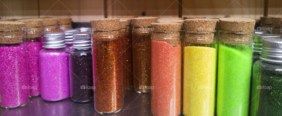 Multicolor dust in small glass bottles. dust for painting anb decoration in shop shelf