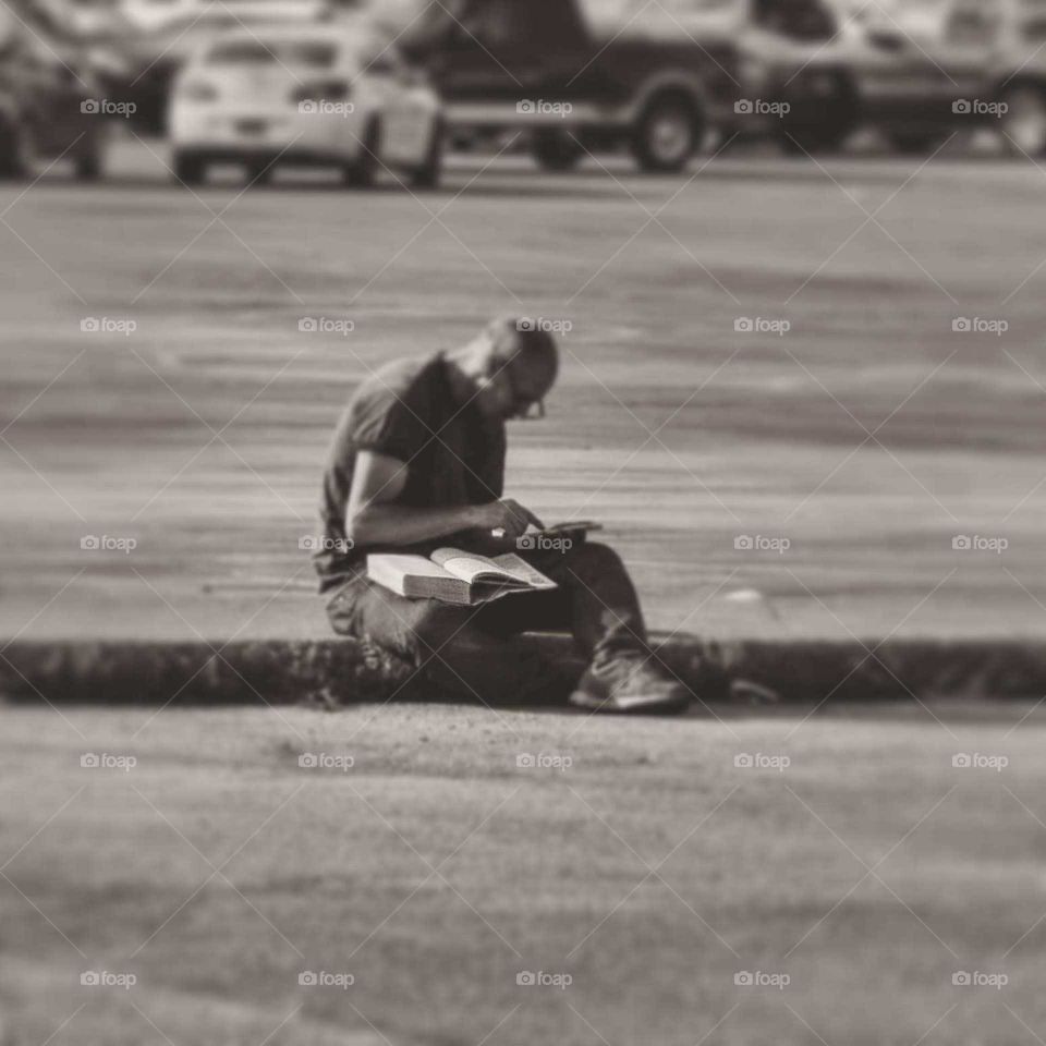 A man studying outside in a parking lot