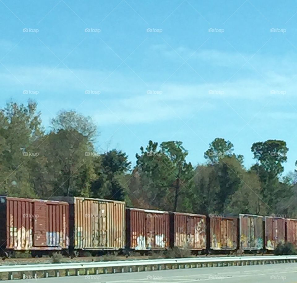 Train on the rail alongside a country road.