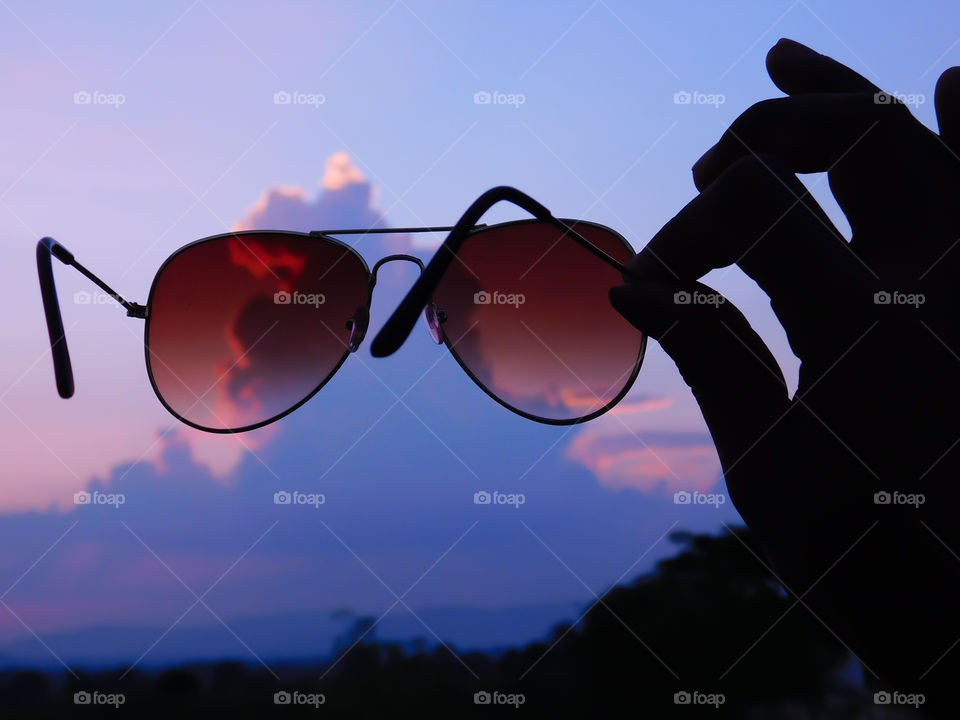 Sunglasses or Eyewear or eyeglasses holding in hand with after sunset golden time and blue time. It is silhouette image. Looking sunset from eyeglasses is my favourite moment in my life.