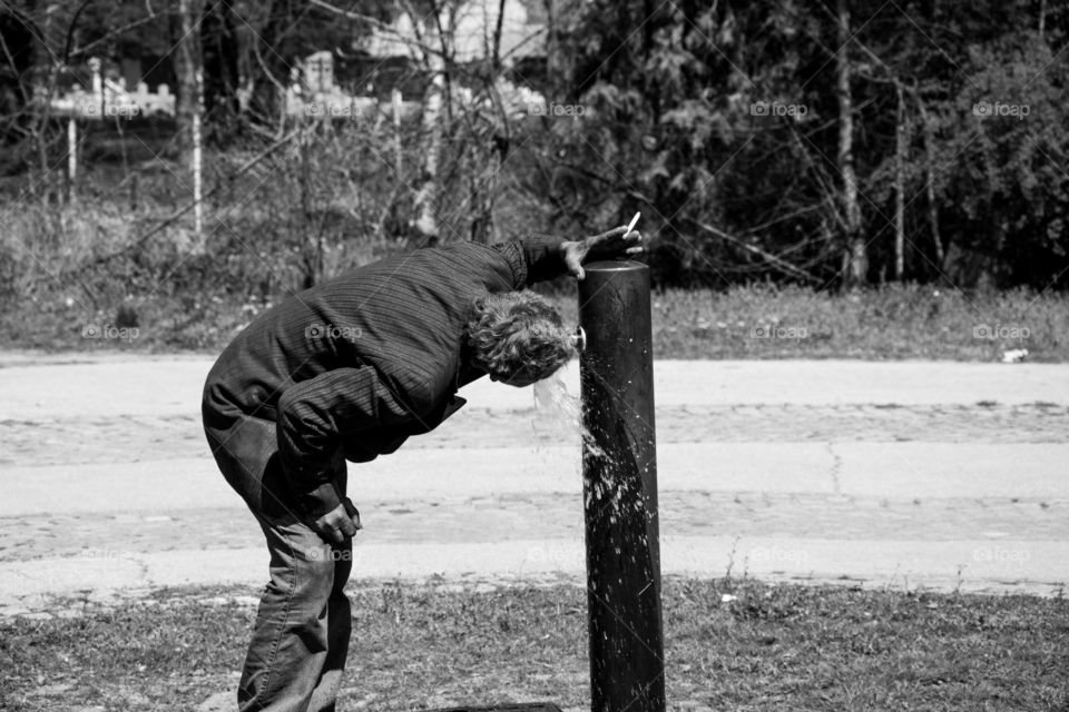 Homeless drinking water in a park