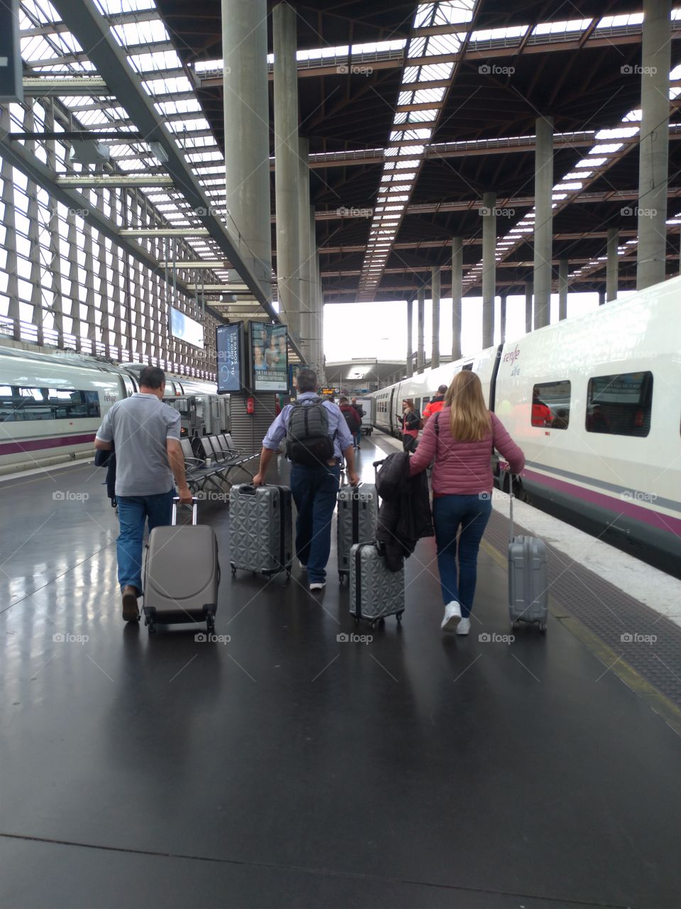 Gente de espaldas con sus maletas van al tren