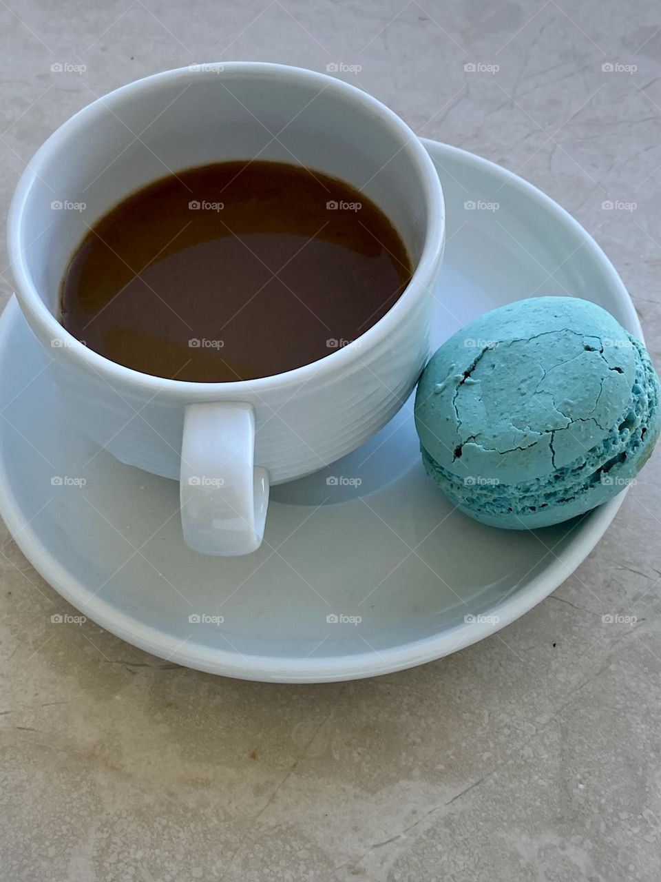 White ceramic cup with coffee and sweet macarons on the table 