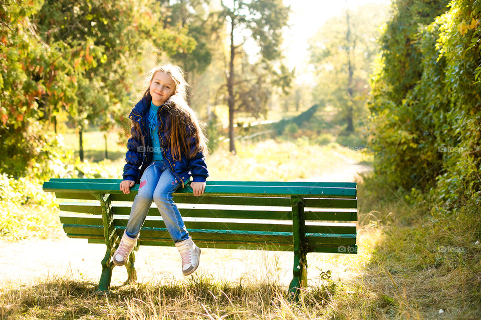 Smiling girl sitting on the bench in park