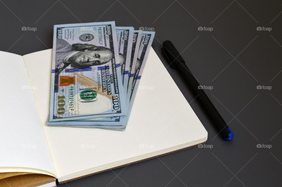 Dollars on the table with a notebook