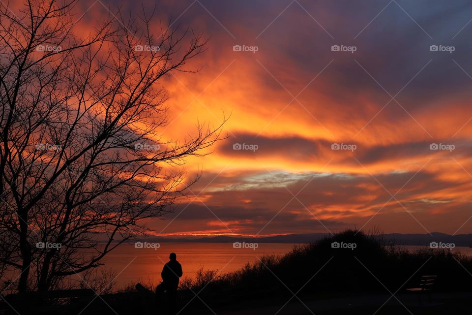 Man by the ocean watching colorful sunset