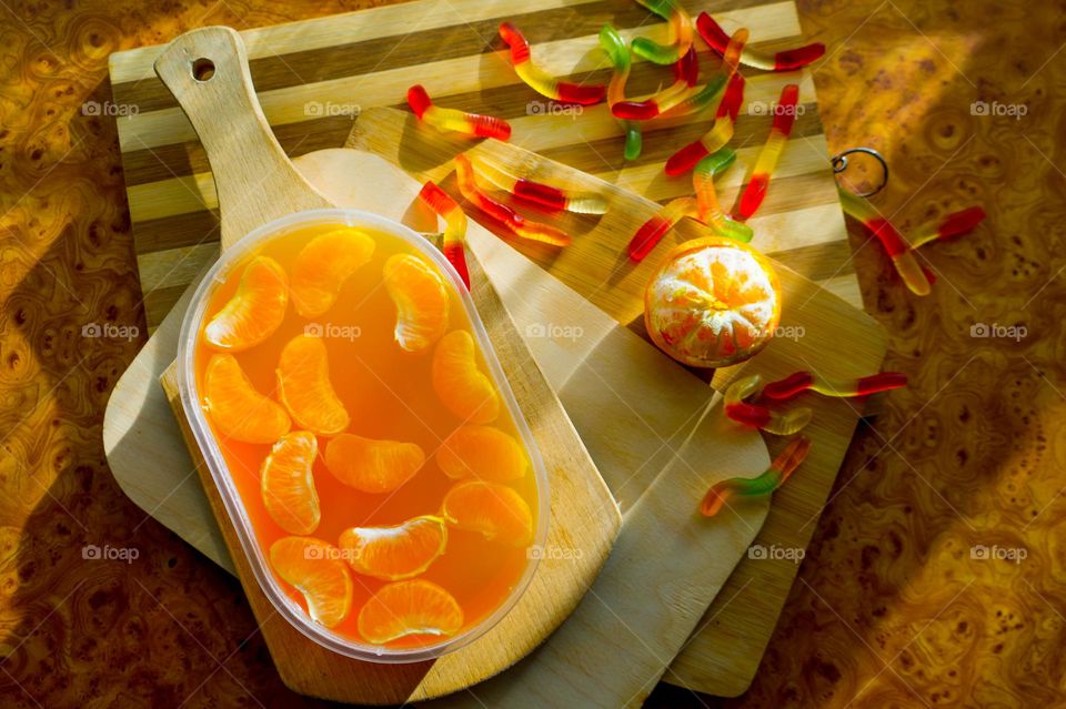 Delicious orange jelly with tangerine slices in a container and jelly worms.
