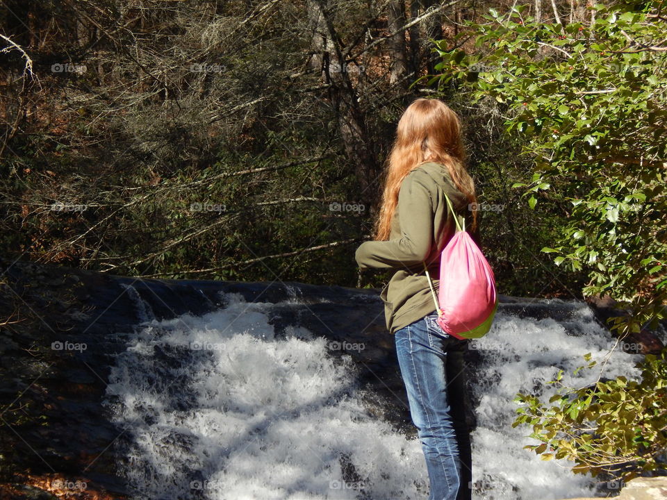 young girl looking at mountain waterfall