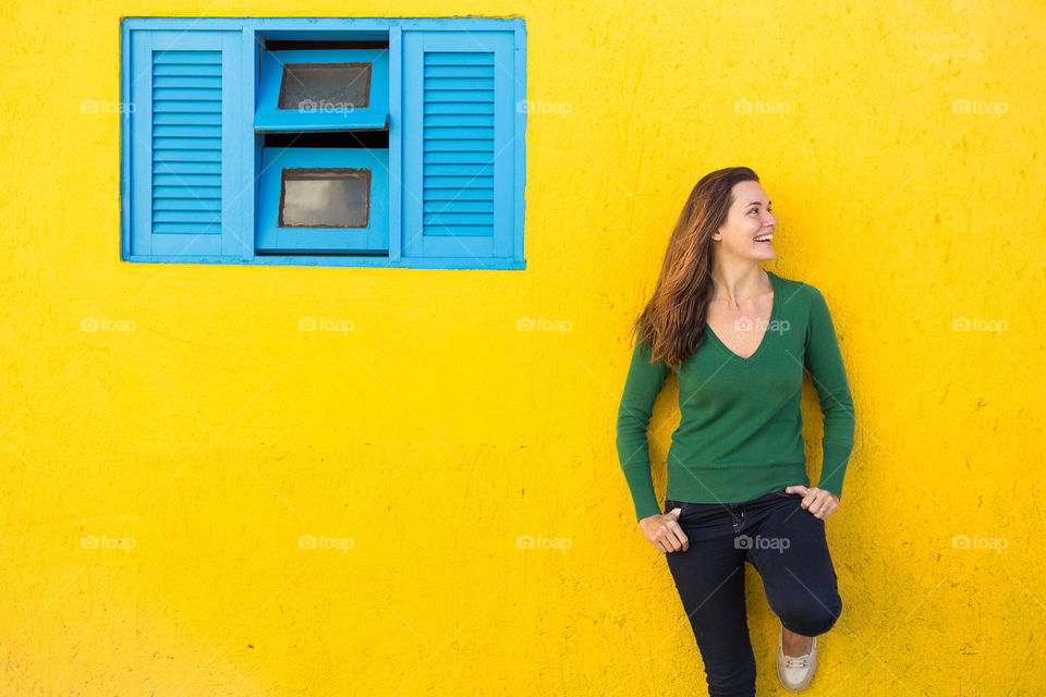Happy woman posing near yellow wall