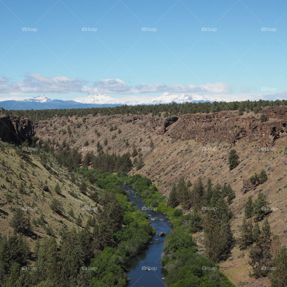 The Deschutes River winds through a canyon in Central Oregon with Cascade Mountains in the background 