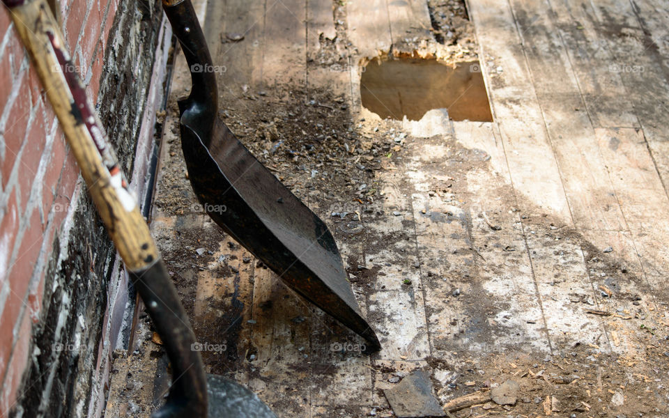 Hole in old Wood building roof with roofers shovels conceptual renovation, construction industry, environmental weathering and vintage building background 