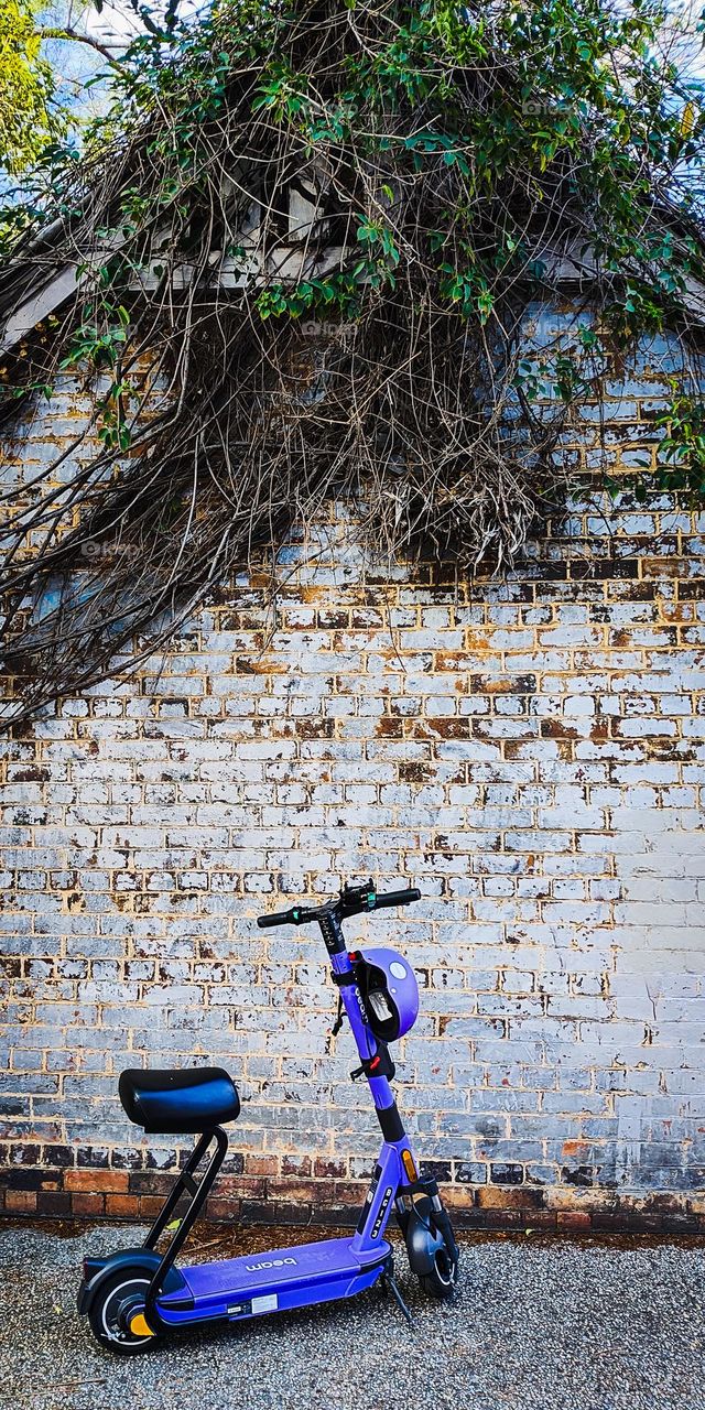 Blue eScooter against old brick house
