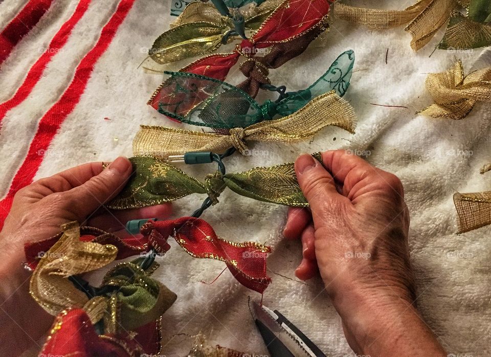 Tying up bows on a string of lights for Christmas  