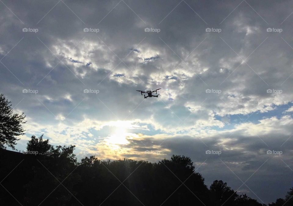 A stealthy drone hovering high above the trees.