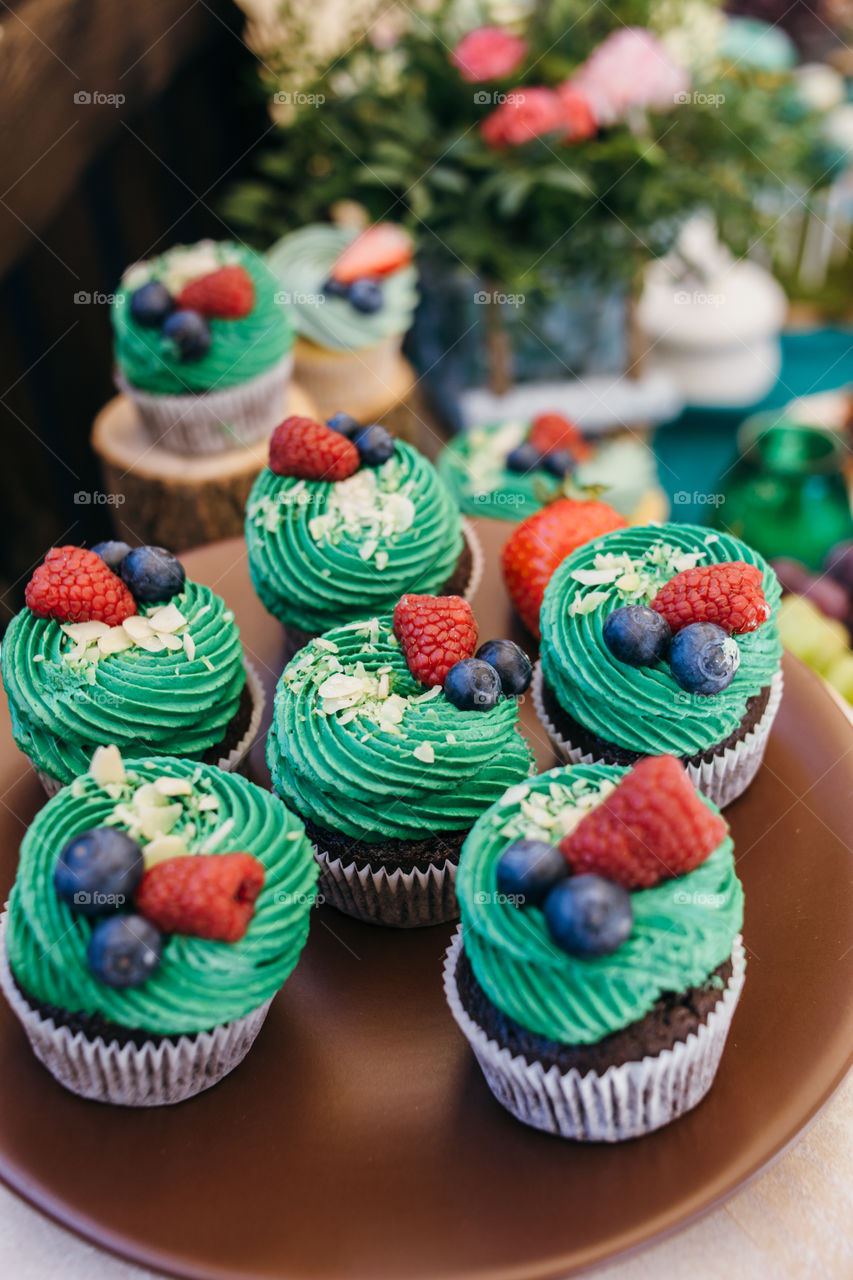 Chocolate cupcakes with green cream and berry fruits