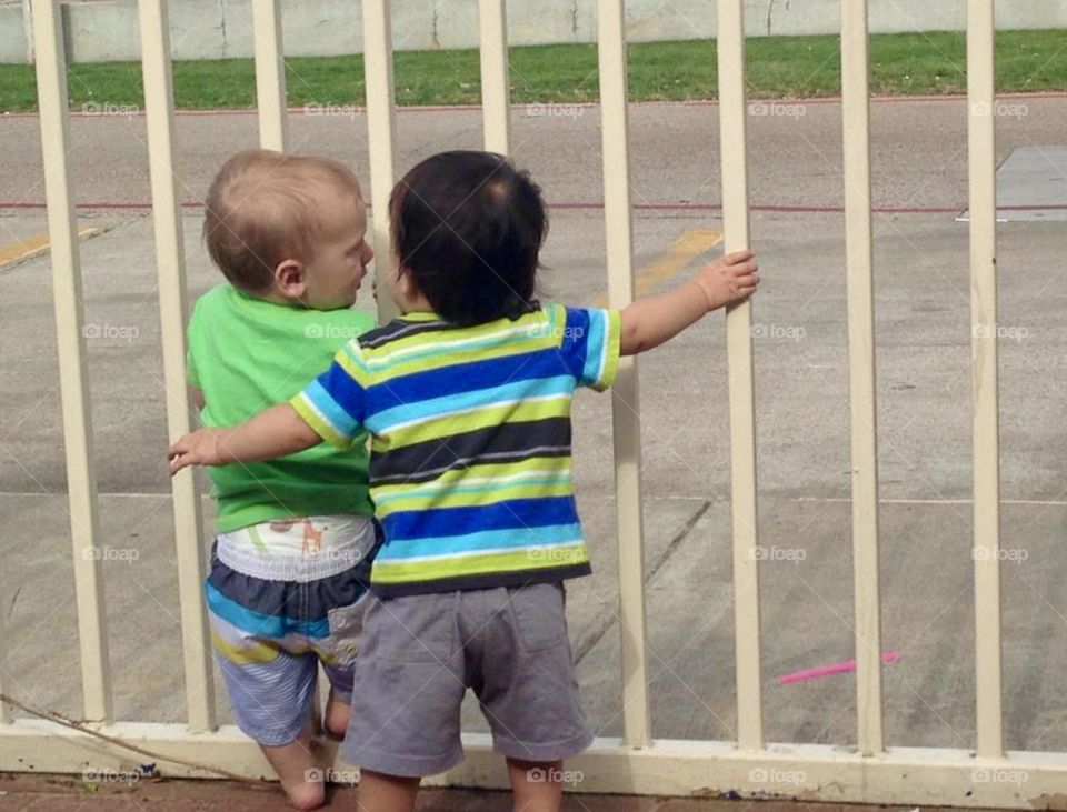 Two toddler boys have a conversation outside after playtime at the splash pad and while waiting for ice cream!