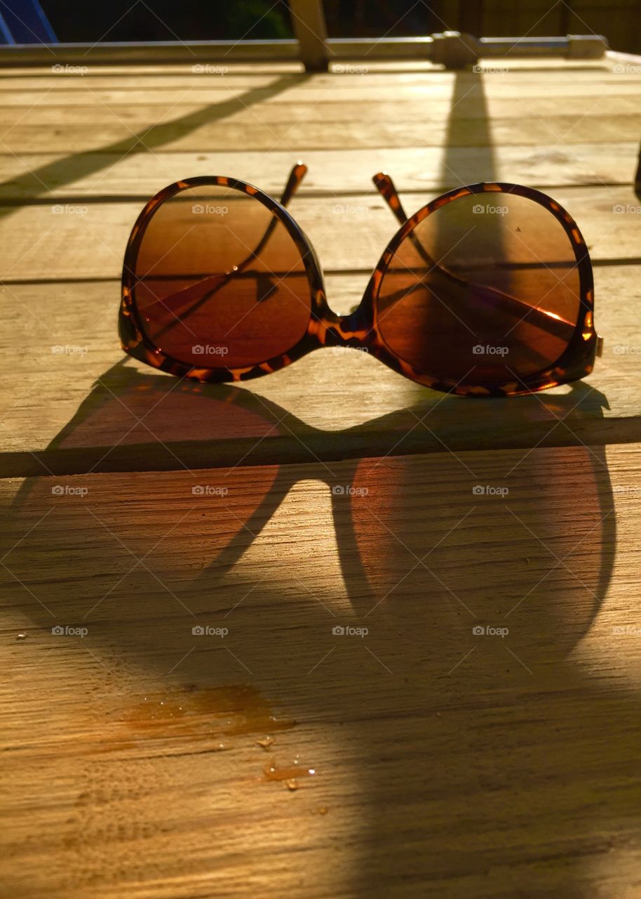 One pair of sunglasses on the deck, with them showing one way and shadow showing the other way making it an oddity. 