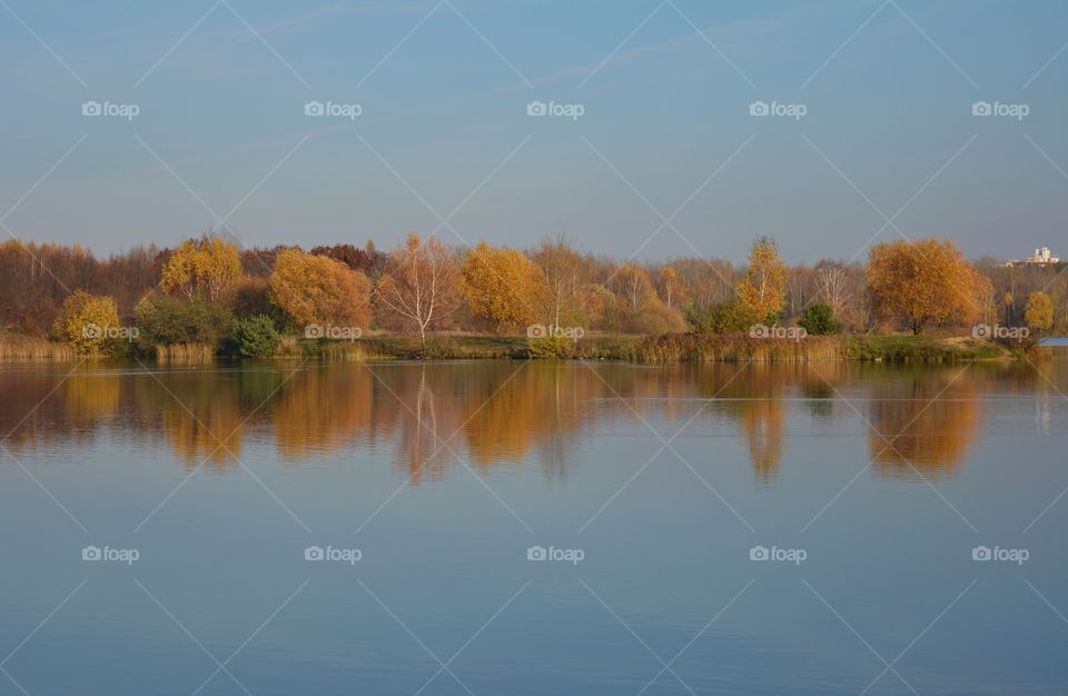 autumn beautiful landscape trees and water lake reflection blue sky background