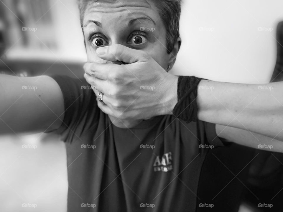 Monochrome selfie of woman with hand over mouth, funny selfie photo in black and white, just shut up selfie 