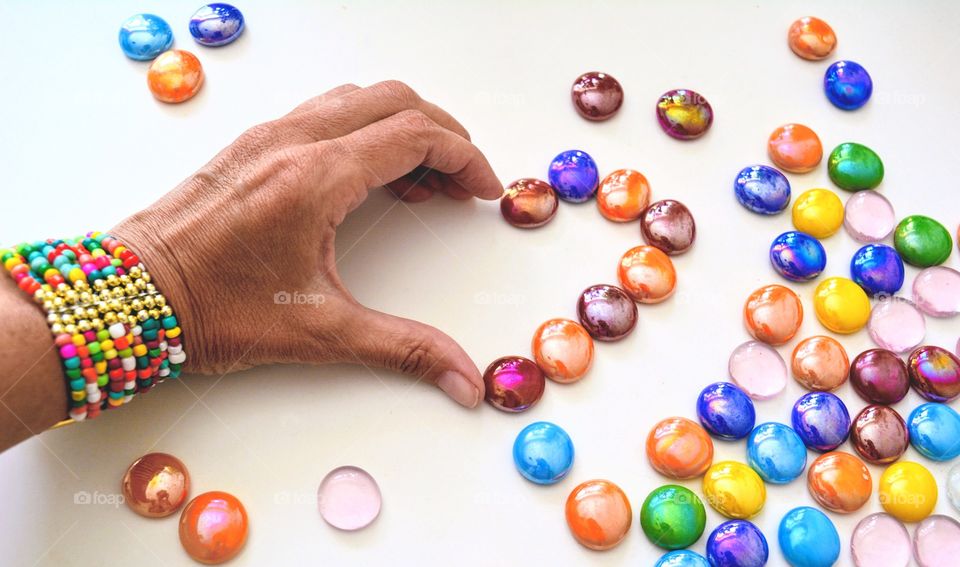 heart of hand and colours decorative stones on a white background, round beautiful texture