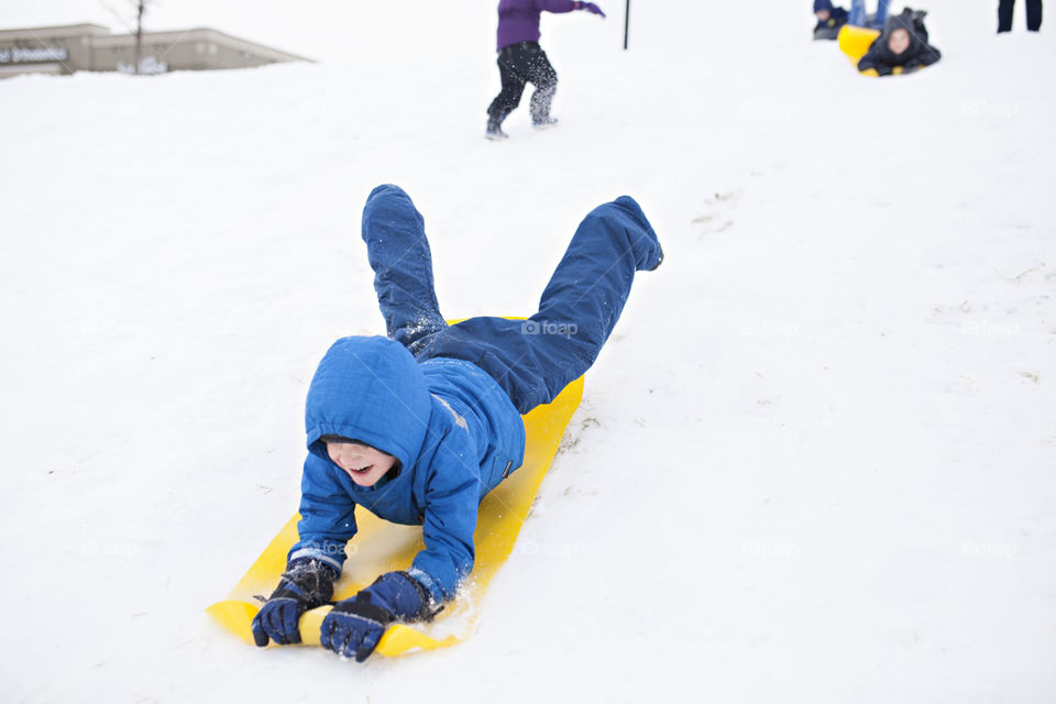 Boy sledding down a hill in the snow 