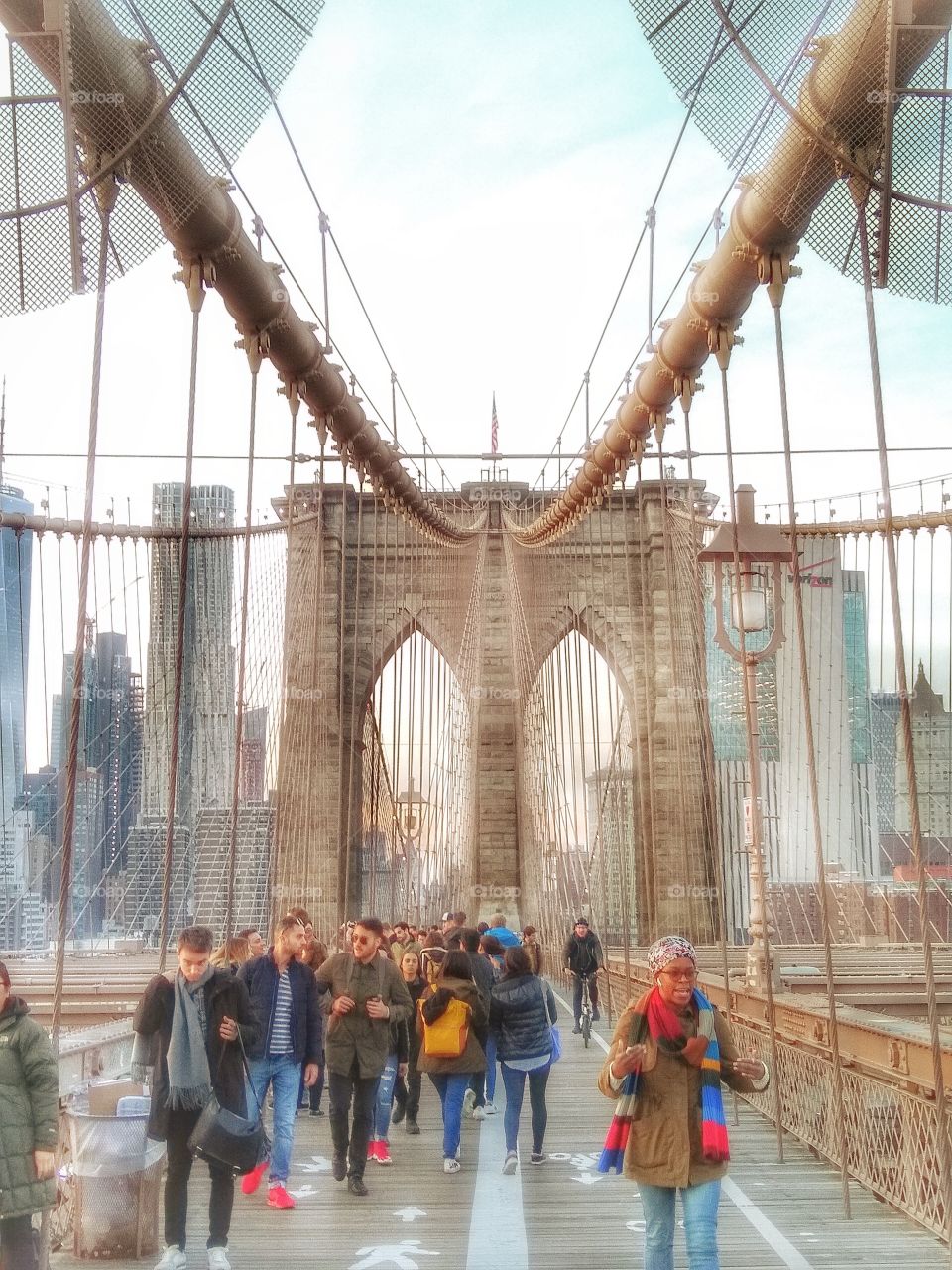 hdr image of unrecognizable people walking over Brooklyn bridge in new york