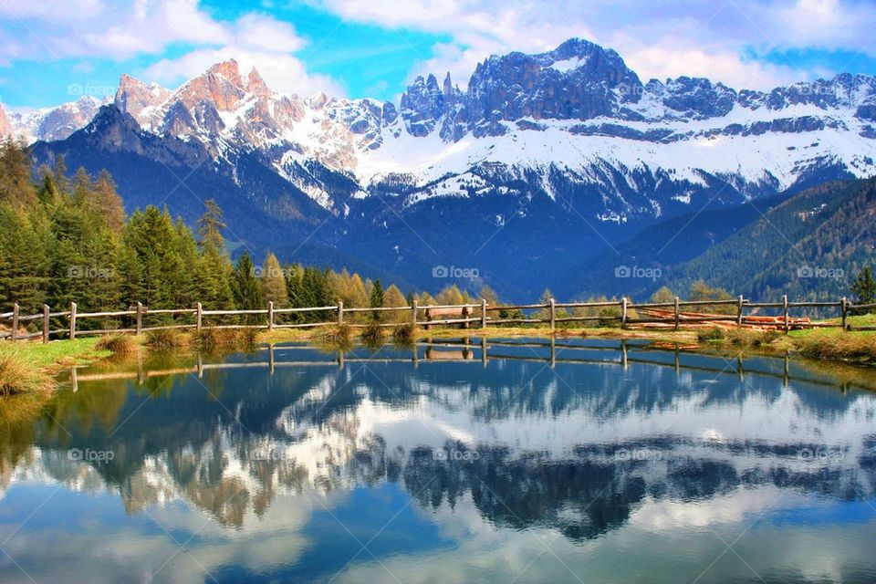 Snowy mountain reflected on lake Carezza