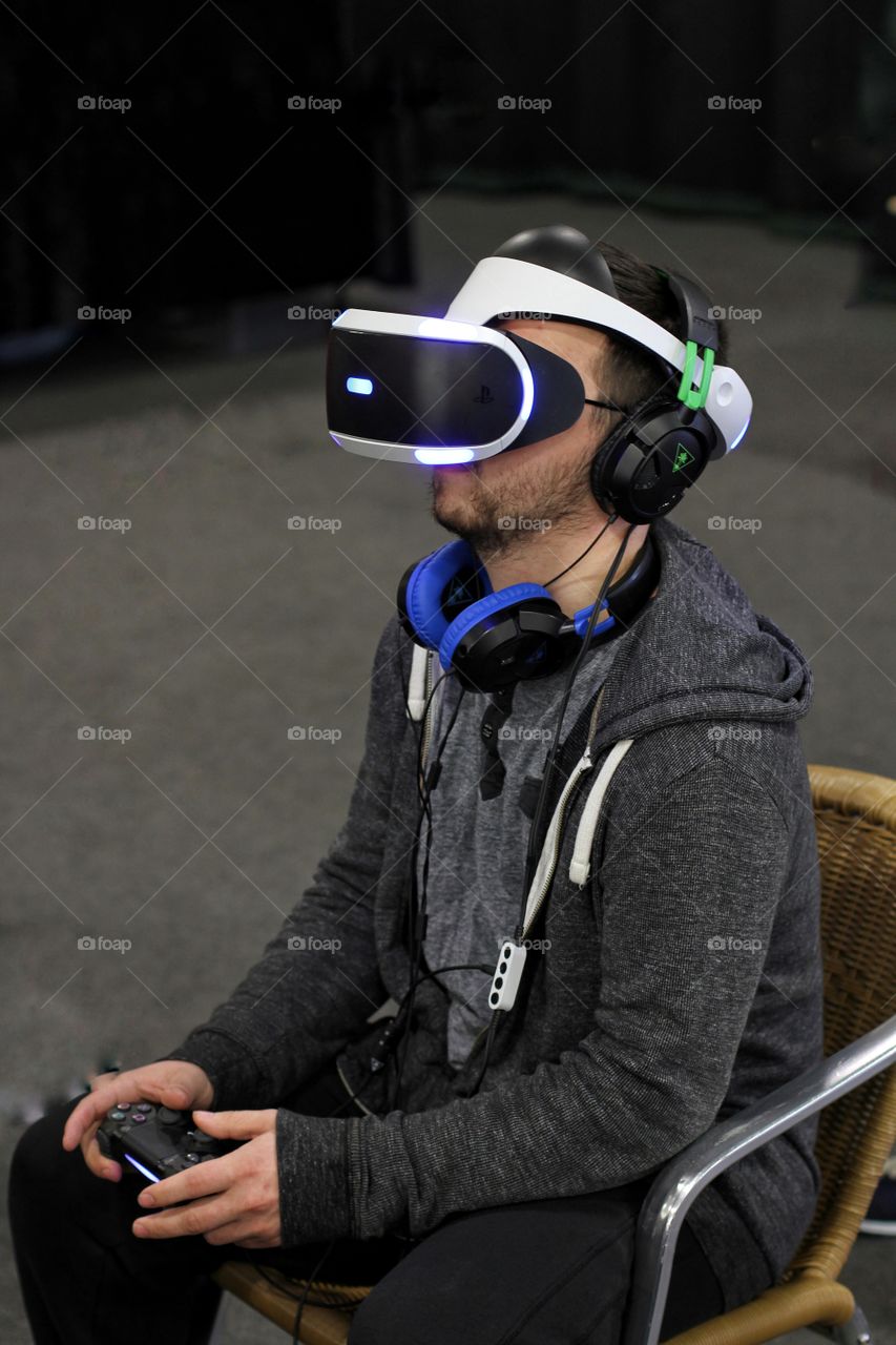 A young man wearing a Virtual Reality headset whilst playing a video game