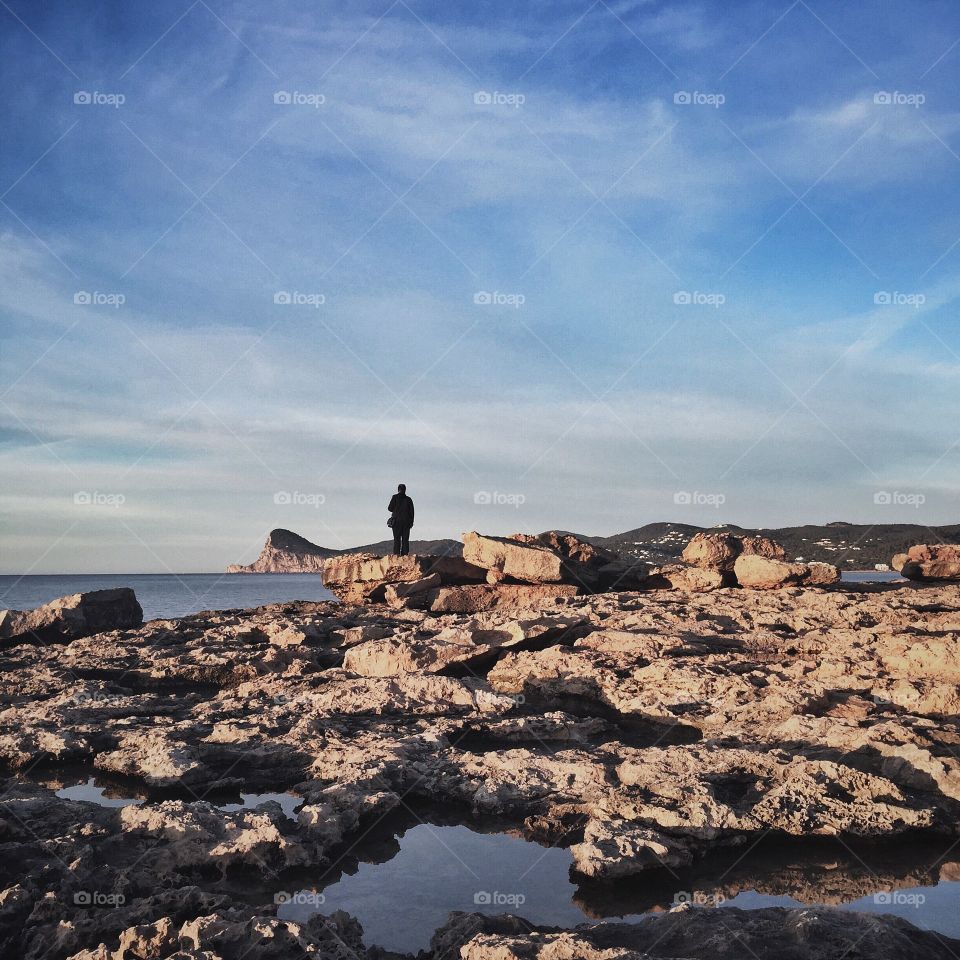 Man by the rocks watching sea