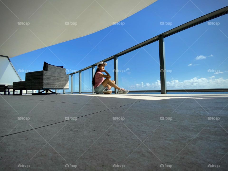 A young adult woman sitting on the balcony floor n a sunny day with a deep thoughts. 