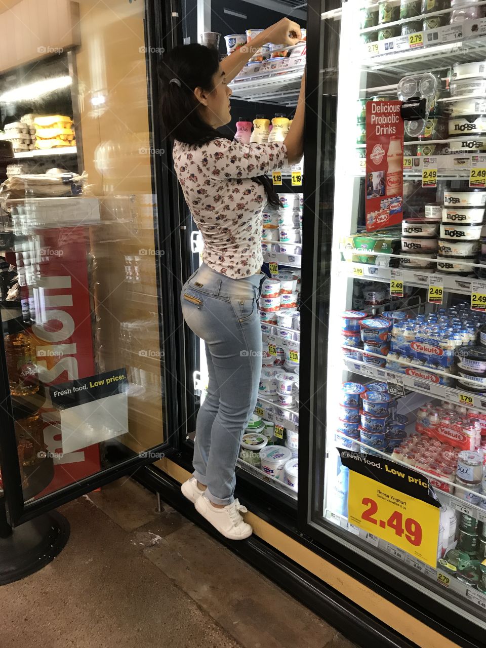 Side view of woman arranging diary products in the refrigerator