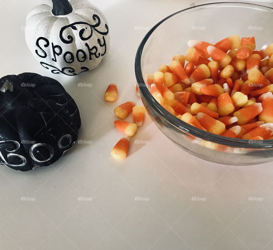 Spooky mini pumpkins with a tasty colorful bowl of candy corns, getting ready for Halloween. 
