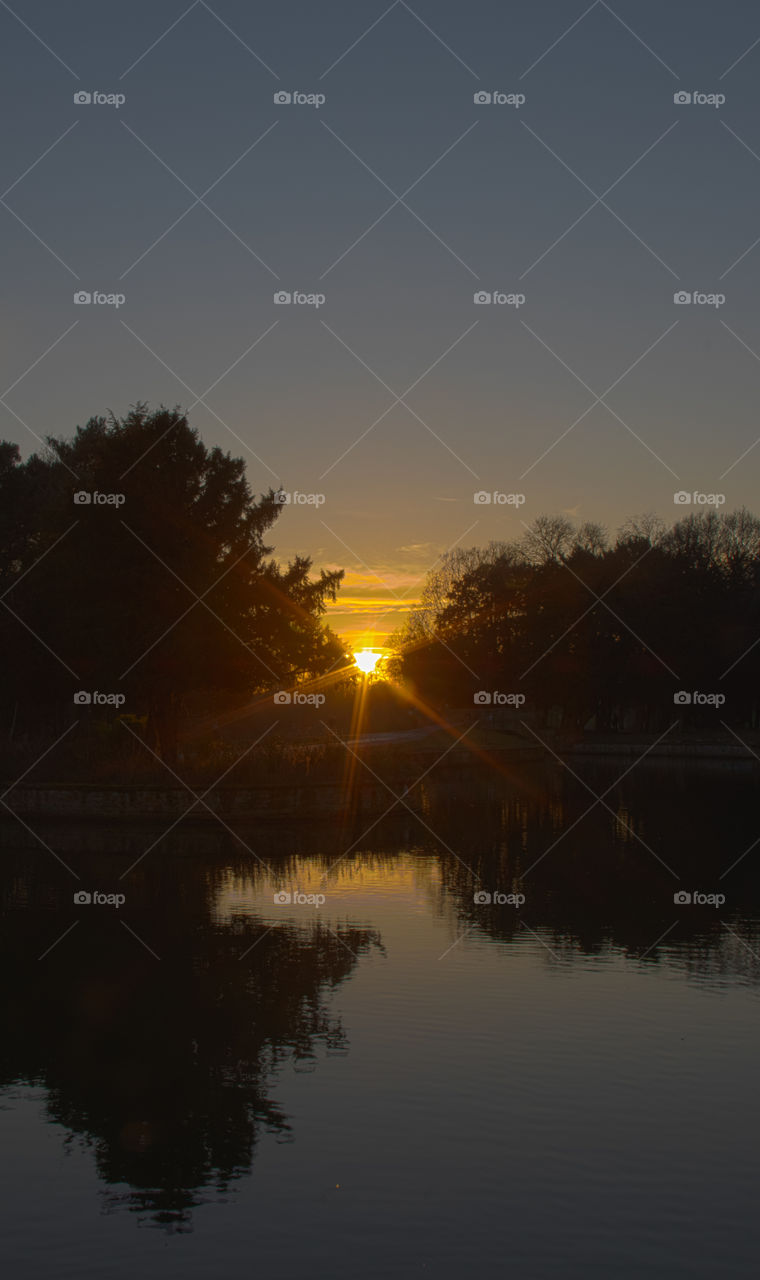 The sun setting on highfeilds boating lake creating a silhouette and starburst effect
