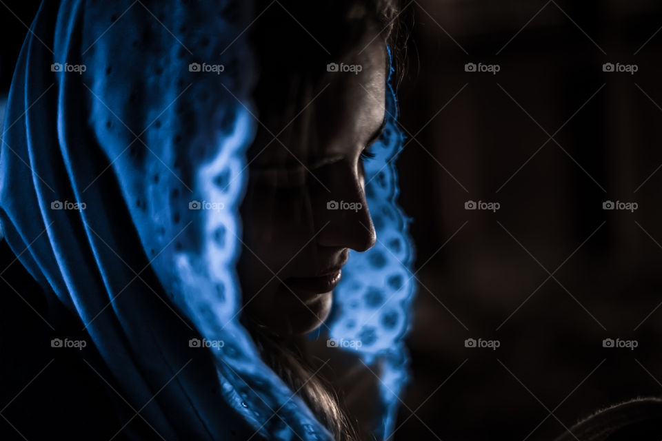 Woman in a blue veil with dark shadows.