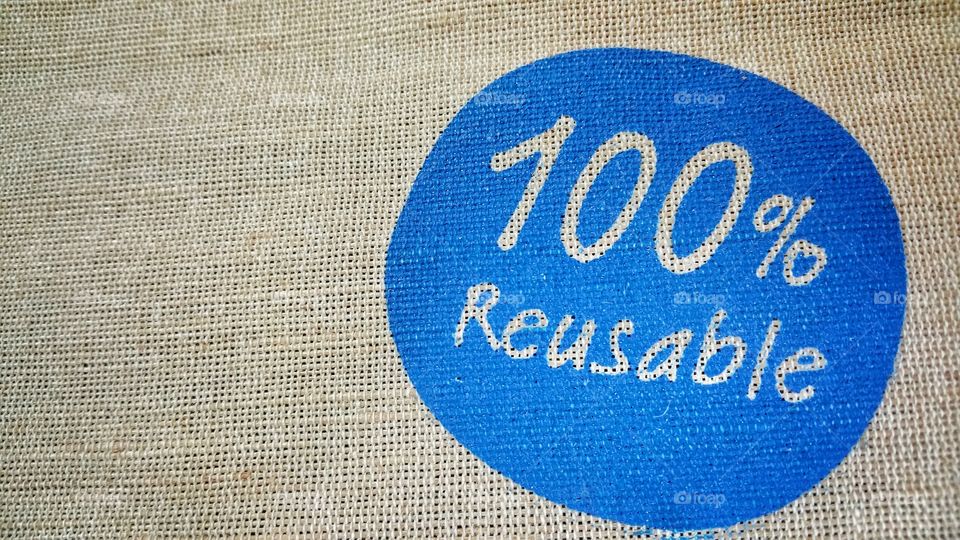 Jute fabric with weaving pattern. A recyclable blue stamp indicating "100% Reusable" is imprinted on it.