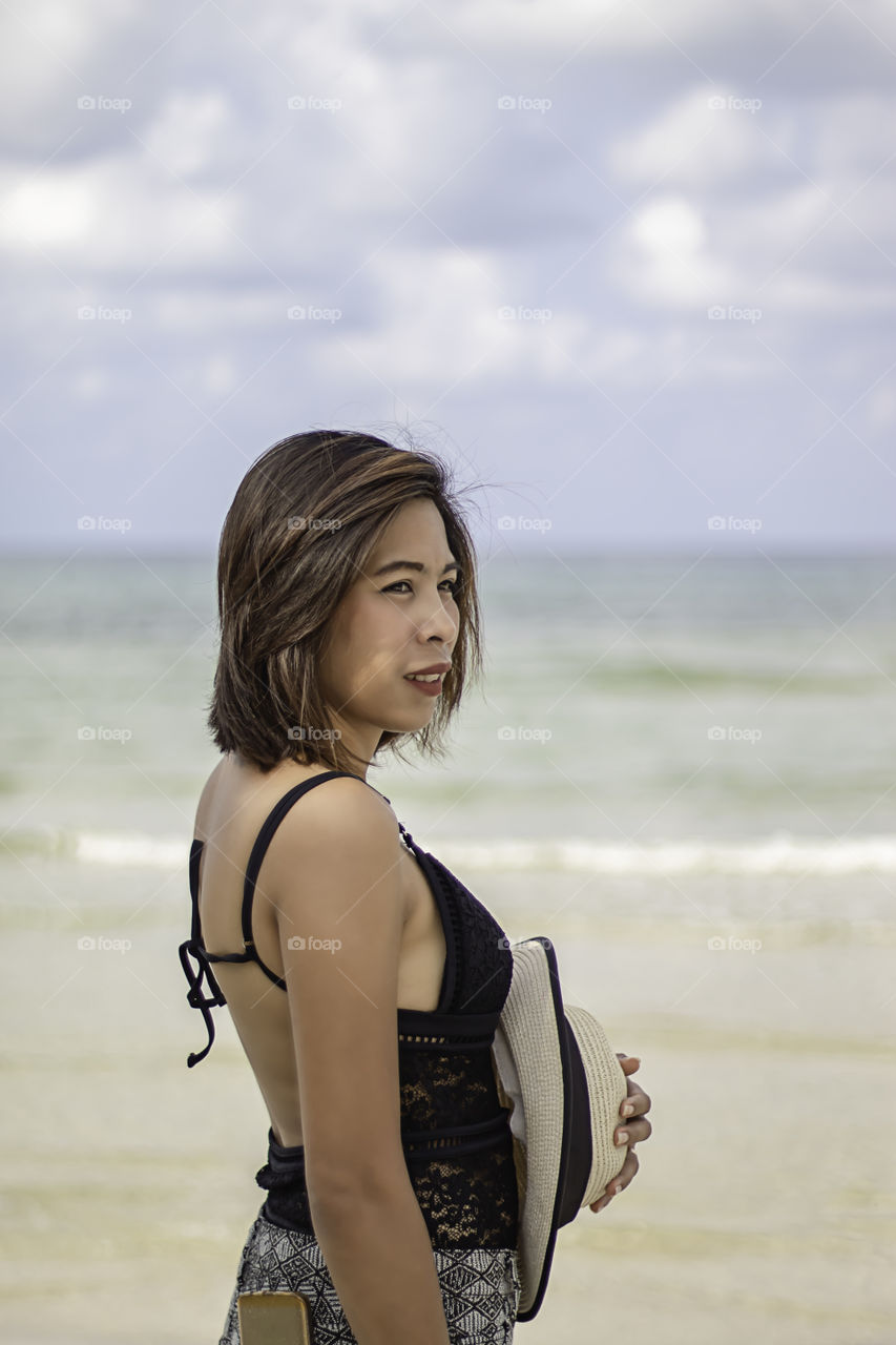 Portrait of Asian woman wearing a swimsuit background sea and sky