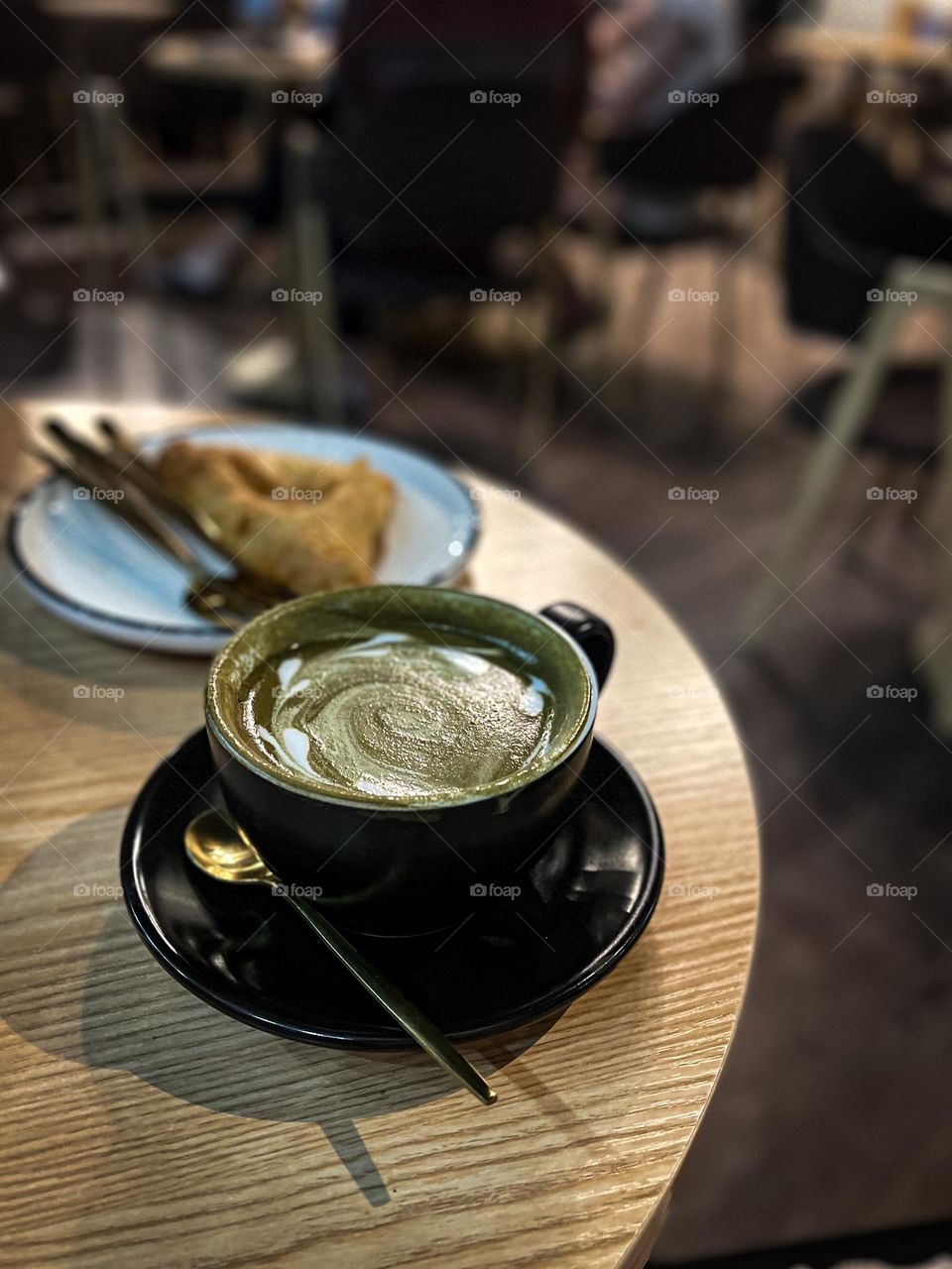 Enjoying hot cup of Matcha espresso in a cafe for breakfast 