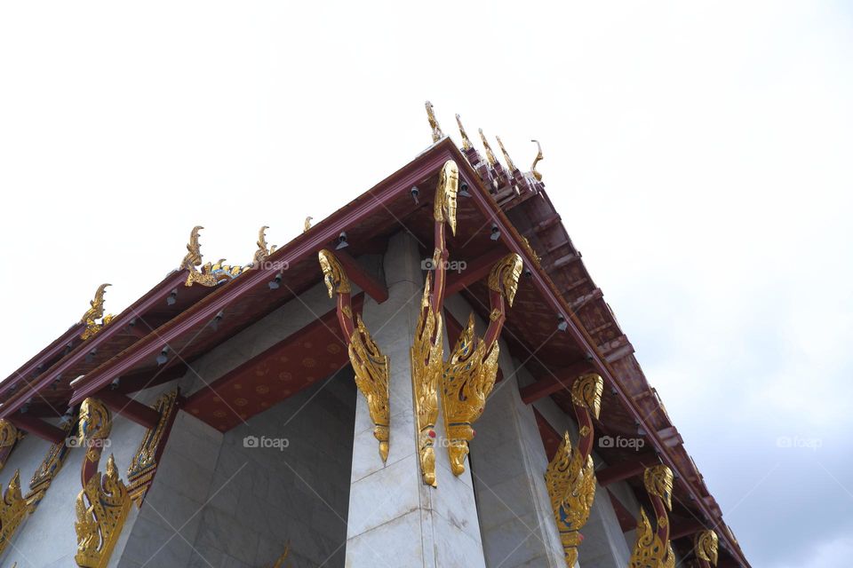 View from below to the pillars and roof of the church of Wat Rakhang Kositaram Woramahawihan in Thailand sky background.