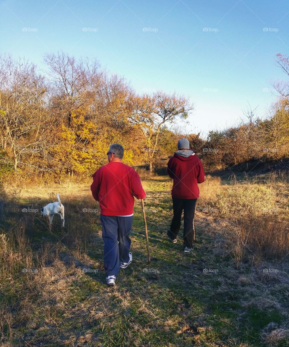 staying in good shape two men taking a hike with their dog in the fall