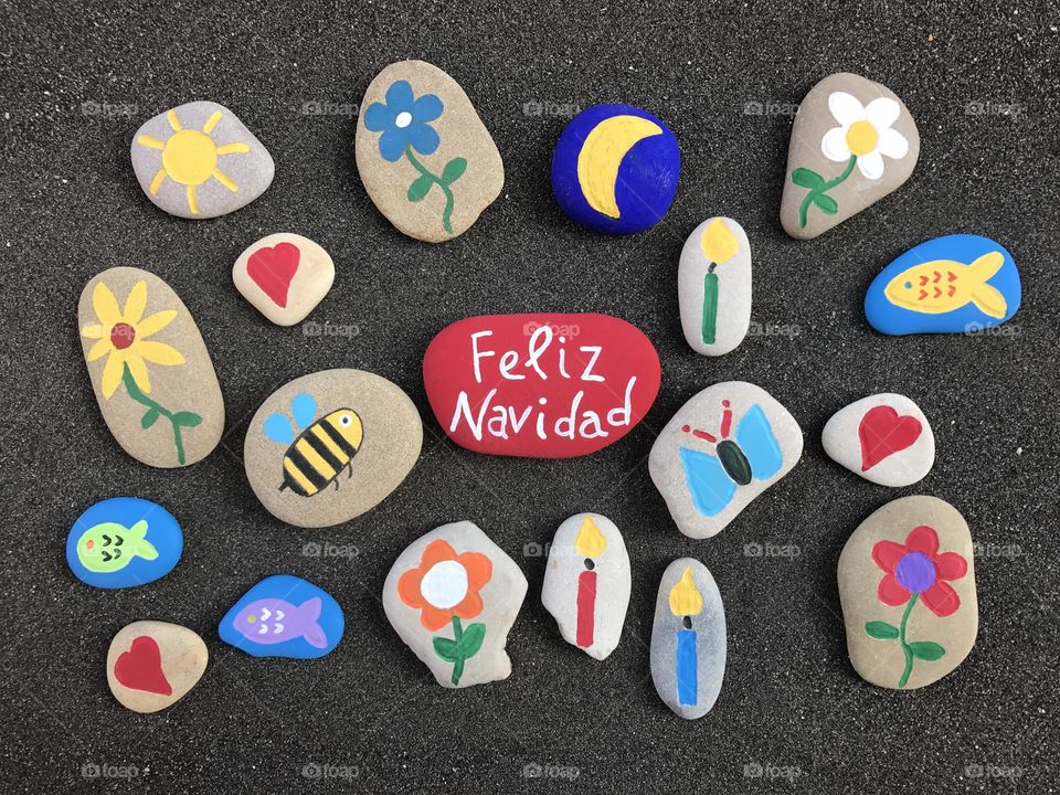 Feliz Navidad, spanish Merry Christmas with stones art over black sand