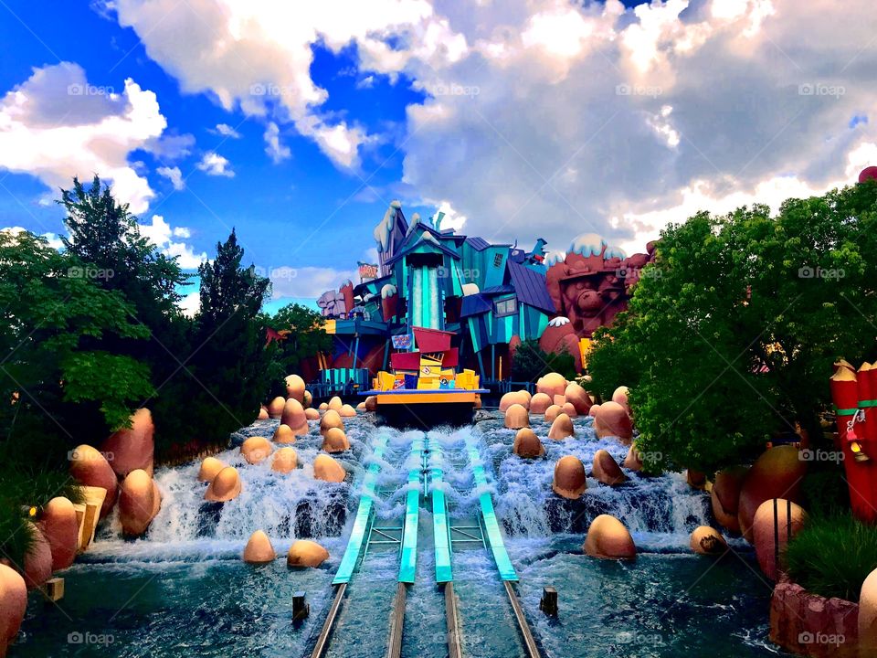 A picture with a lot of color. Here you see a water attraction in universal studios. You can also see the green nature and the blue sky with nice clouds.