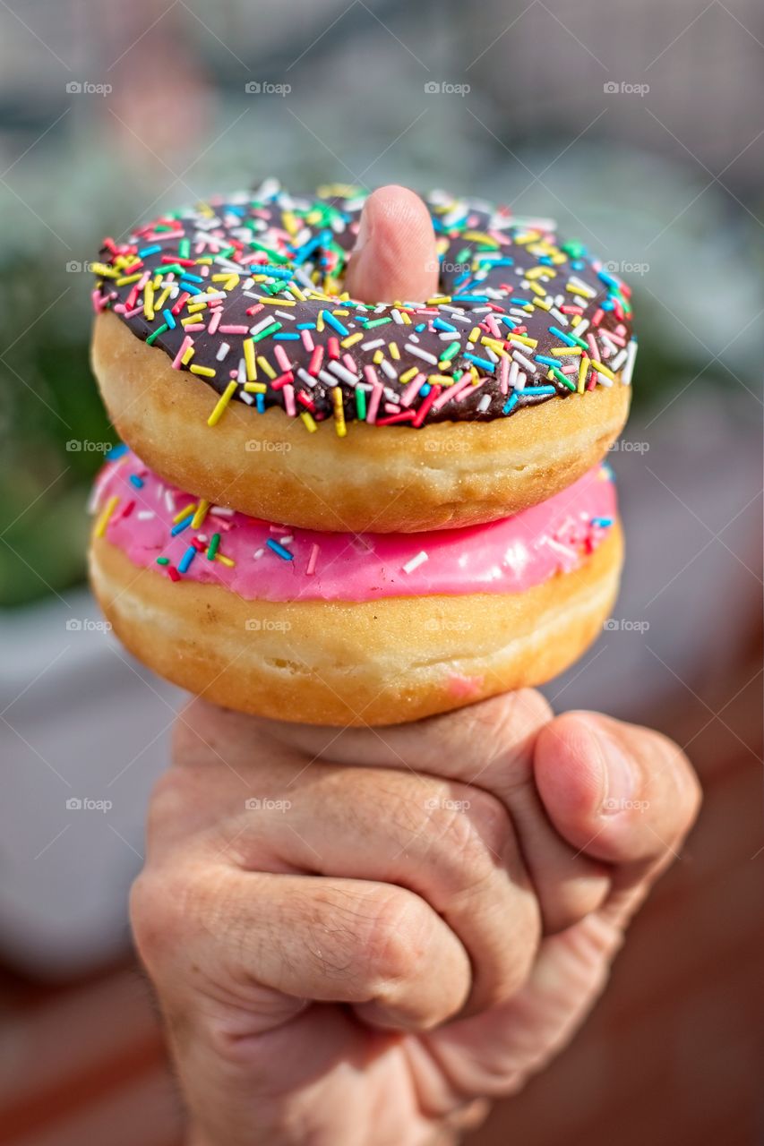 Finger holding two colorful and tasty donuts